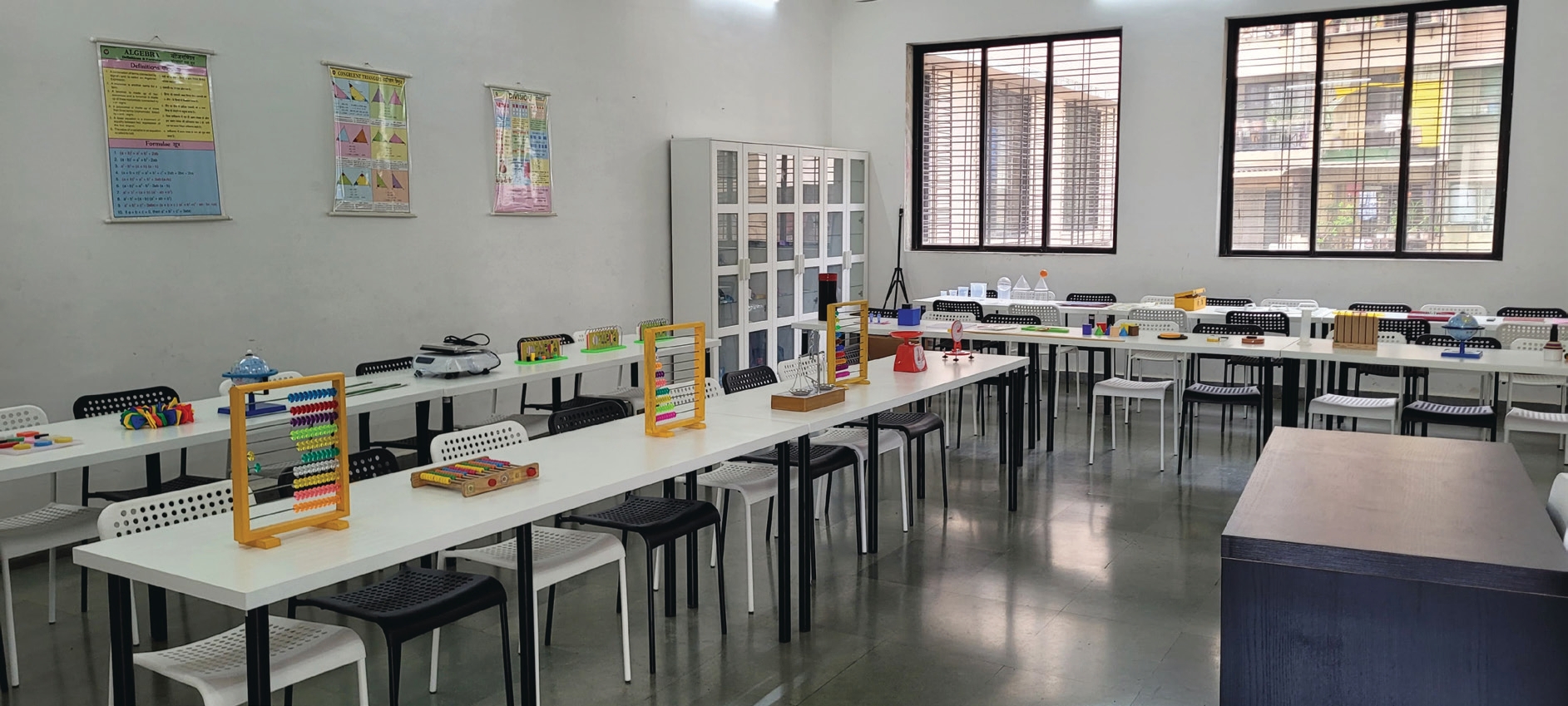 “Modern mathematics lab classroom with tables, chairs, and learning tools like abacus and educational models